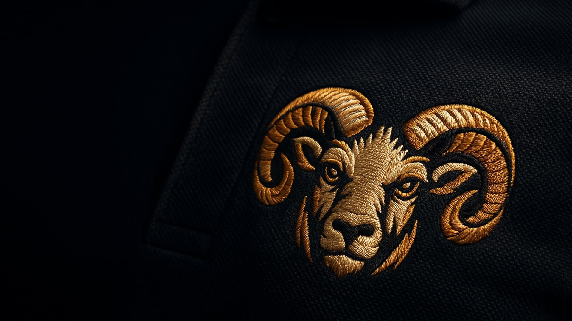 The Bighorn Threads ram logo embroidered in gold thread on a navy company polo